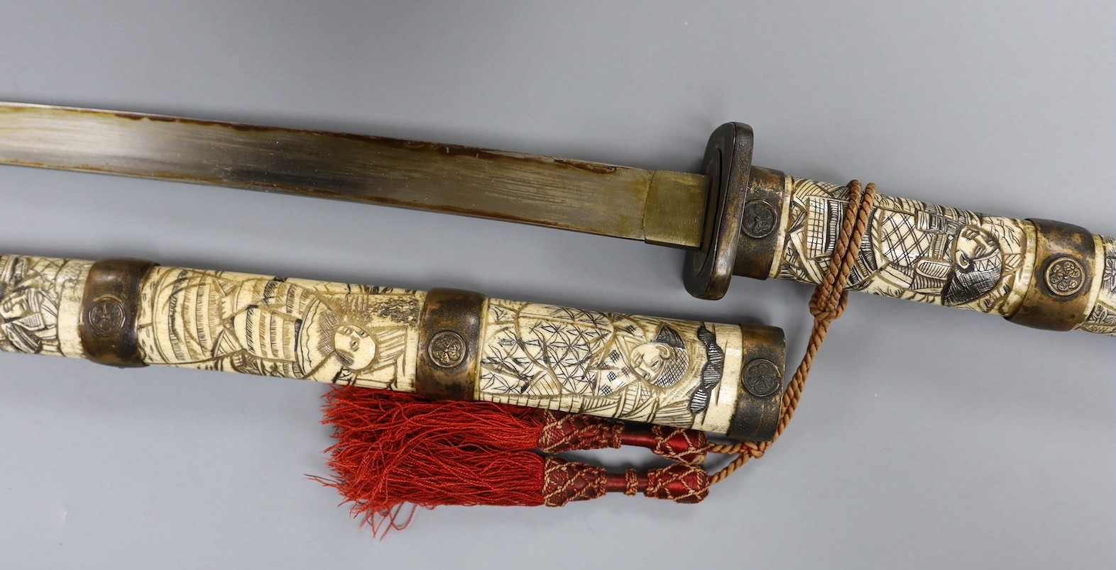 A late 19th century Japanese wakizashi sword, the blade 47.5cm, with sectional stag's horn scabbard and hilt carved with warriors and other figures, gilt metal mounted